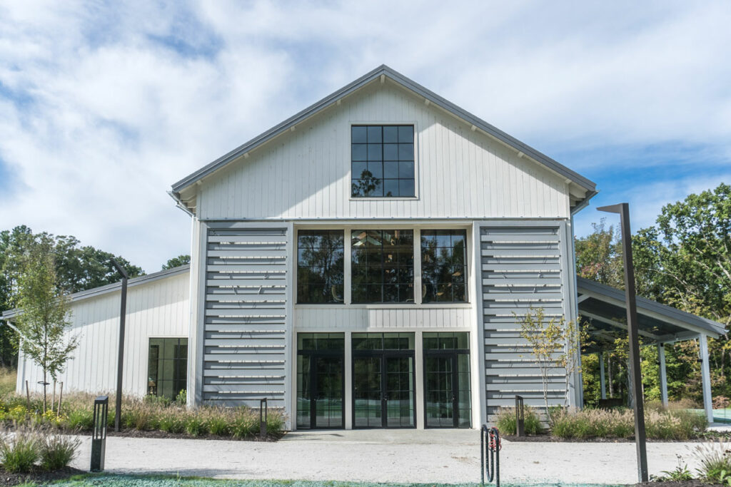 An exterior picture of Hope Church in Richmond, Virginia, designed and built by Geobarns, with white wood siding, gray metal roof, long monitor cupola, exterior rolling barn door shutters,.