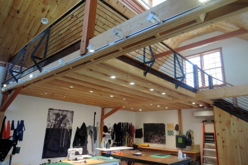 An interior picture of Judy Kirpich's quilting studio, design and built by Geobarns, showing a floating loft office above the art studio.