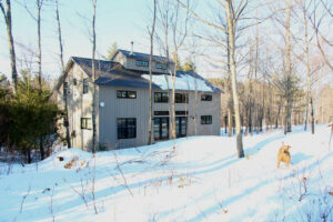 GeoBarns, mountaintop New Hampshire home, exterior snow, gray siding, windows, french doors