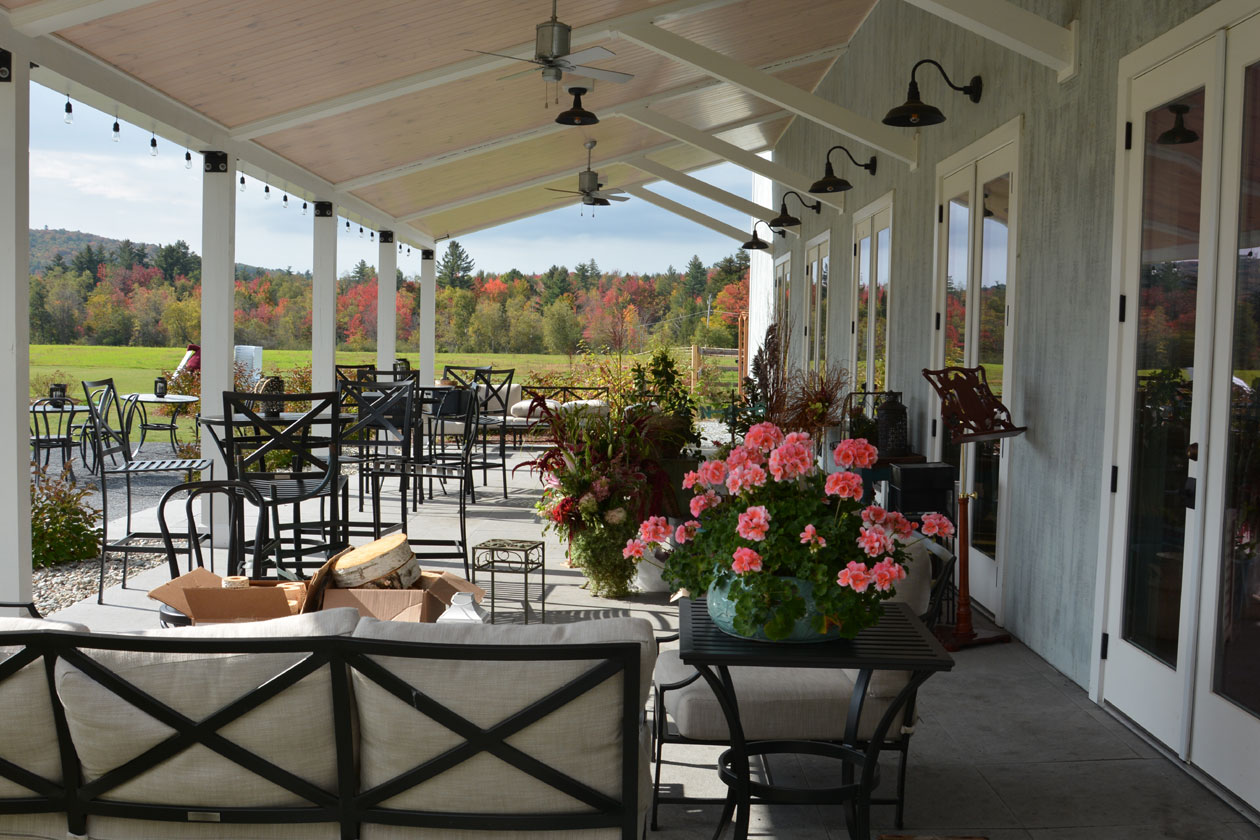 The vernadah at the Barn at Smuggler's Notch wedding and event venue, decorated with flowers, with outdoor seating.