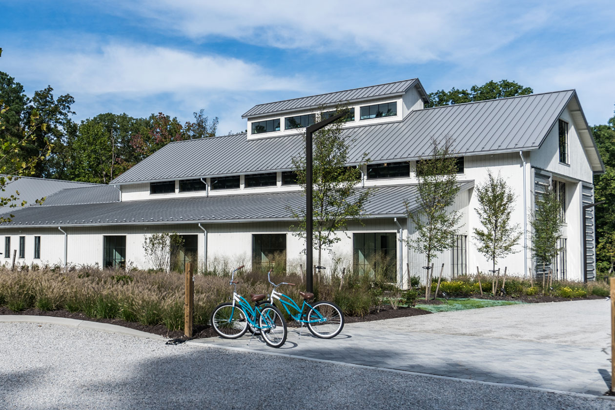 An exterior picture of Hope Church in Richmond, Virginia, designed and built by Geobarns, with white wood siding, gray metal roof, long monitor cupola, exterior rolling barn door shutters, and two bicycles parked out front.