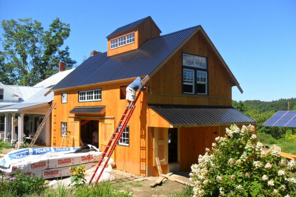 A Geobarns garage and office addition under construction showing siding and trim being installed.