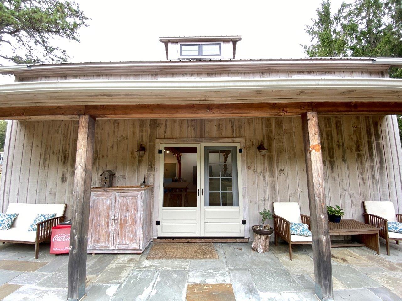 An exterior picture of the porch of Jessica Pisano's art studio with retro furniture and an antique Coca-Cola cooler.o