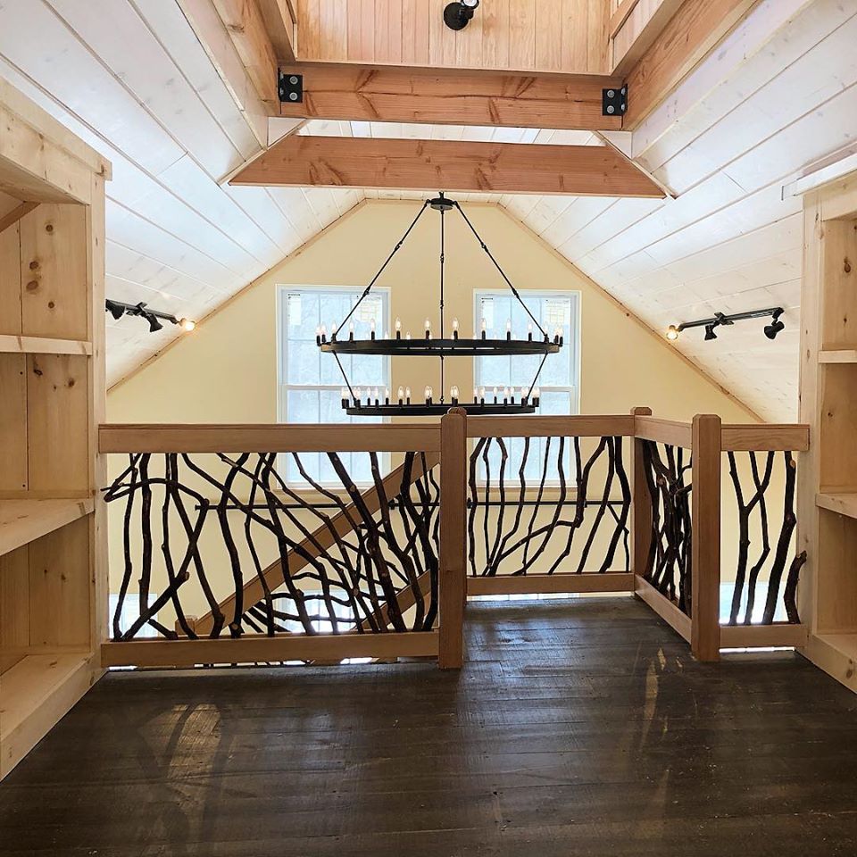 A picture of a staircase designed and built by Geobarns, using tree limbs as balustrades, with custom-built bookshelves.