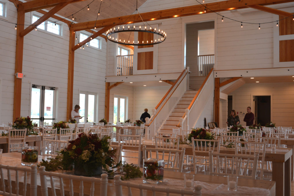 A picture of a banquet in a Wedding Barn in Vermont with people setting up decorations