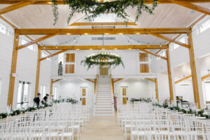 A picture of a banquet hall in a Wedding Barn in Vermont with white chairs and two women setting up decorations