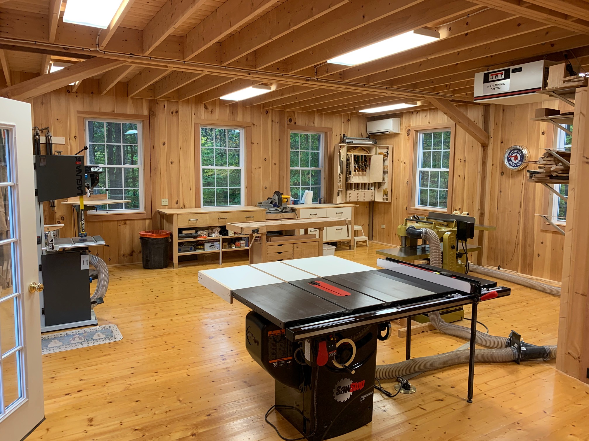 An interior picture of a custom woodworking shop, design and built by Geobarns, showing careful layout of sop equipment and dust collection system.