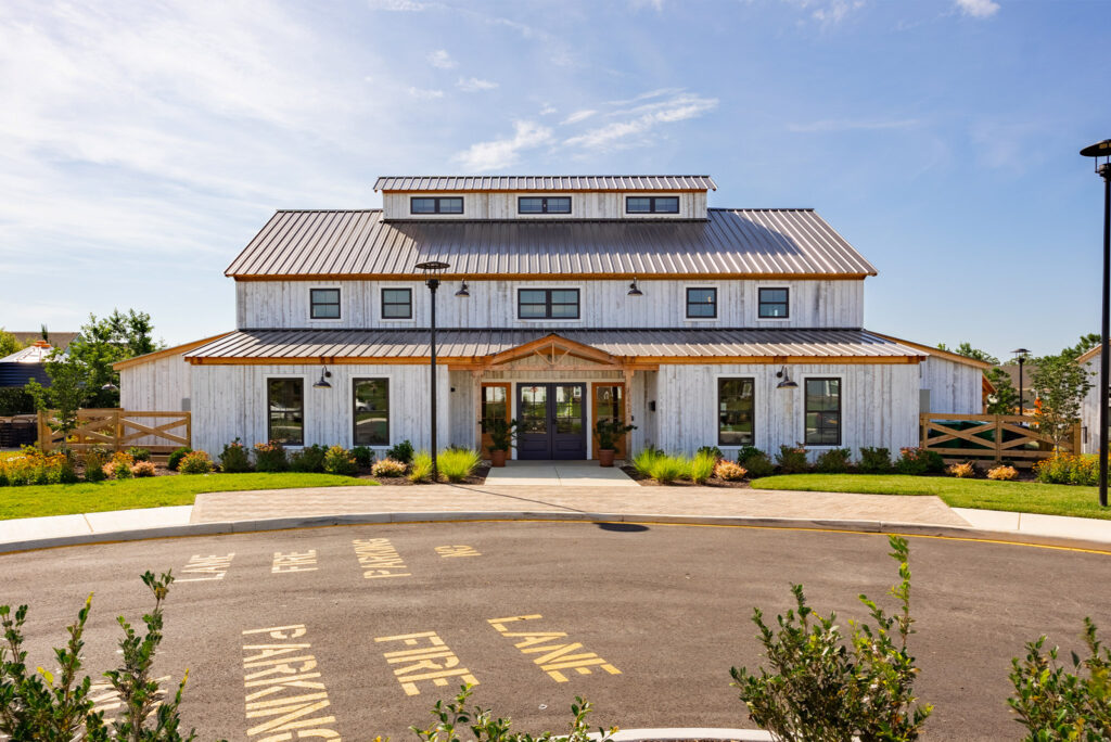 An exterior picture of The Farmhouse at Chickahominay Falls, designed and build by Geobarns, with Windswept recycled wood siding, burnished bronze metal roof, and long monitor cupola.