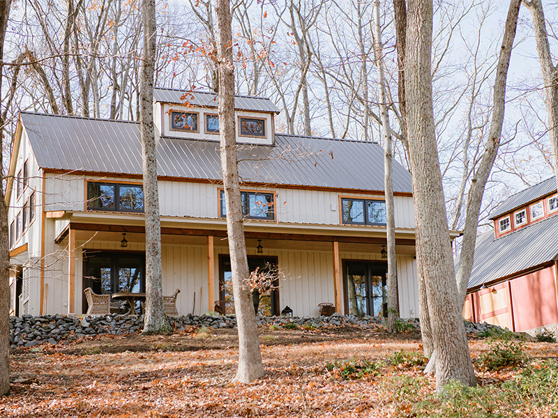 A picture of the Modern Farmhouse and Shop Barn, with light gray wood siding and metal roof in burnished bronze, designed and built by Geobarns in Bundoran Farms conservation community in Virginia.