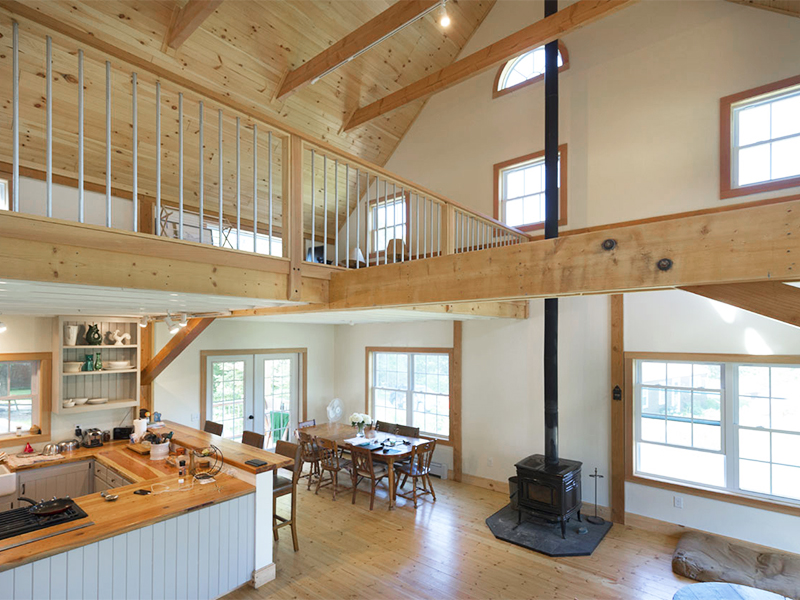 An interior picture of the Organic Farmhouse, designed and built by Geobarns, featuring vaulted ceilings and exposed framing timbers.