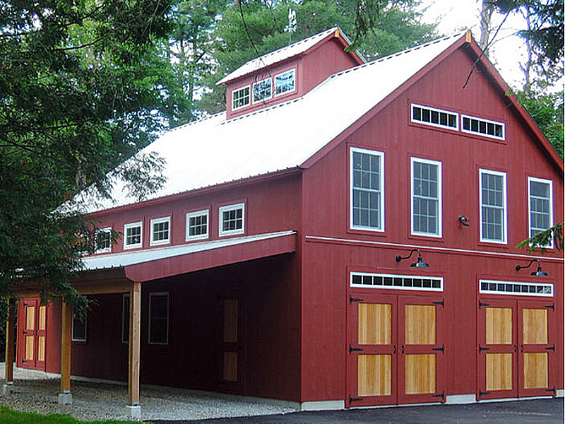 An exterior picture of a dream garage designed and built by Geobarns, with barn red siding and silver roof, hand-built garage doors, and a side awning for additional storage.