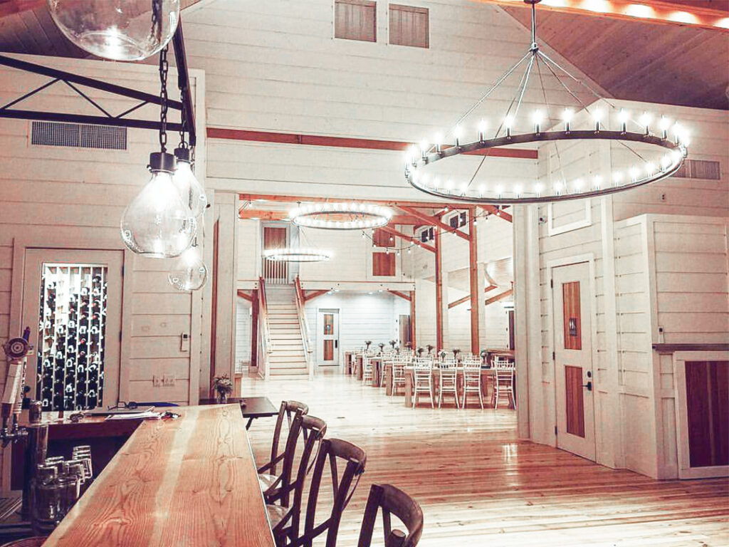 An interior picture of the Barn at Smuggler's Notch showing the bar, grand hall, wagon wheel lights, and pendant lights made from old wine bottles.s.