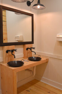 A picture of a vanity in a bathroom with twin iron skillet sinks and a mirror