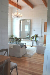 A picture of a room in a Wedding Barn loft with a chandelier, a mirror, a loveseat, and chairs