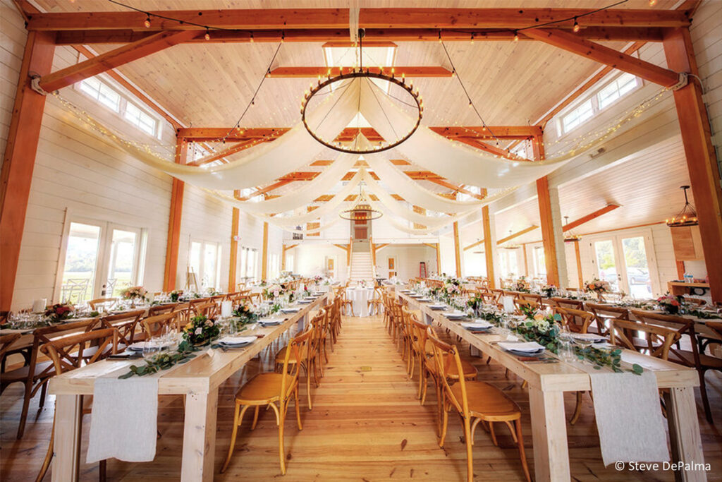 The stunning interior of the Barn at Smuggler's Notch, designed and built by Geobarns, set up for a wedding banquet.