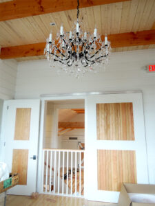 A picture of a balcony in a loft in a Wedding Barn in Vermont with a rolling barn door and a chandelier