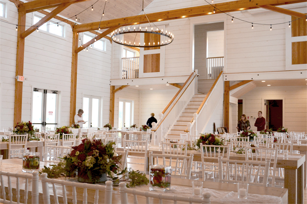 A picture of a banquet in a Wedding Barn in Vermont with people setting up decorations