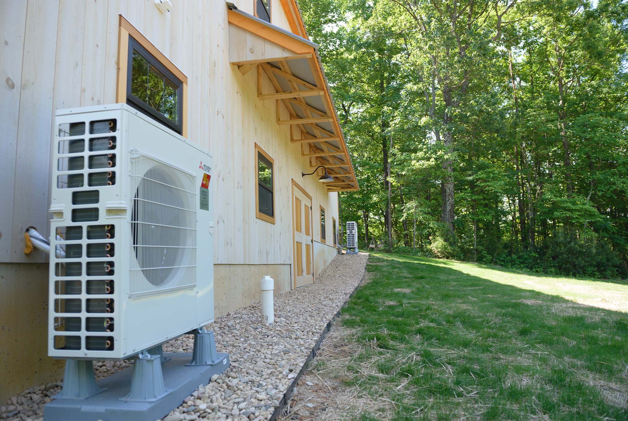 An exterior picture of a fine furniture maker's workshop showing Mitsubishi high-efficiency heat pumps.